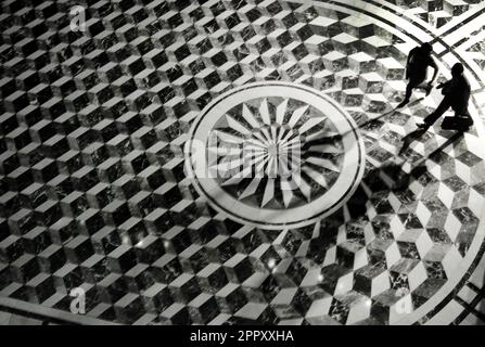 Overhead view of a male and female executives walking across an ornate tile floor Stock Photo