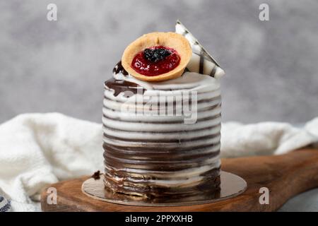 Cream cake surrounded by chocolate. Chocolate cake on gray background. Studio shoot. Bakery products. Close up Stock Photo