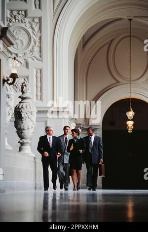 A group of determined african-American and Caucasian executives walking through an ornate lobby Stock Photo