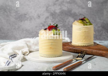 Cream cake surrounded by chocolate. Chocolate and fruit cream cake on gray background. Studio shoot. Bakery products Stock Photo