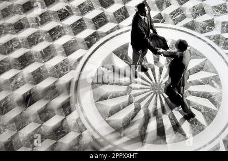 Overhead view of an African-American and Caucasian businessmen shaking hands while standing on an ornate lobby floor Stock Photo