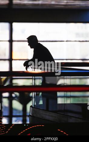 Silhouette of a troubled business executive insured leaning against the railing of corporate office building Stock Photo