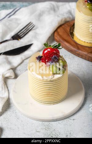Cream cake surrounded by chocolate. Chocolate and fruit cream cake on gray background. Studio shoot. Bakery products Stock Photo