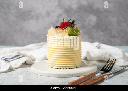 Cream cake surrounded by chocolate. Chocolate and fruit cream cake on gray background. Studio shoot. Bakery products Stock Photo