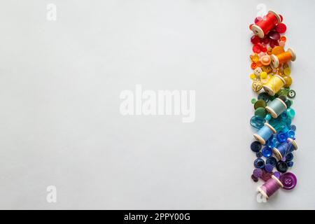 Buttons, colorful threads ,pins laid out on a white background as a rainbow spectrum. Copy space. Stock Photo