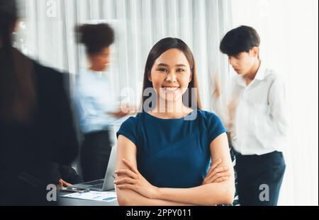 young asian businesswoman portrait poses confidently with diverse coworkers in busy meeting room in motion blurred background multicultural team 2ppy011