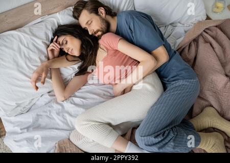 Top view of man in pajama hugging girlfriend while sleeping on bed,stock image Stock Photo