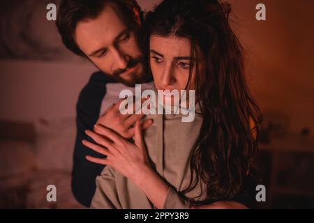 Bearded man hugging sad girlfriend at home in evening,stock image Stock Photo