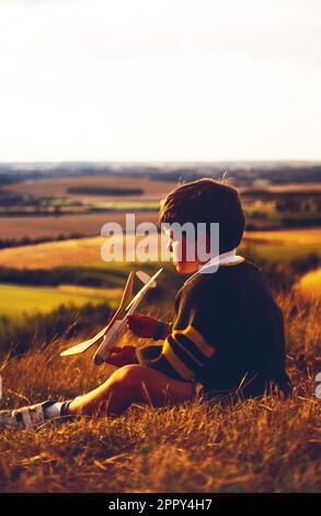 England. Children. Boy sitting on hillside with his model plane. Stock Photo