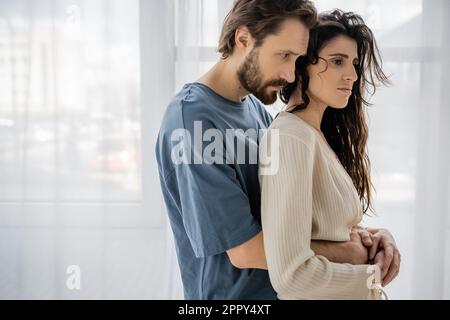 Caring bearded man embracing sad girlfriend at home,stock image Stock Photo