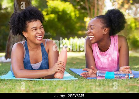 Two young Black friends chat and drink water after exercise session in park yoga Stock Photo