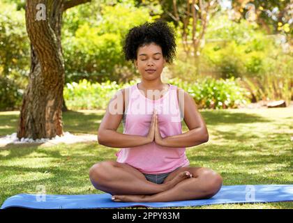 A young woman sits in prayer pose in beautiful garden in summer Stock Photo  - Alamy