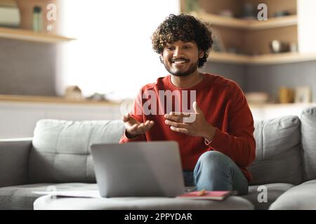 Smiling young indian man making video call with laptop at home Stock Photo