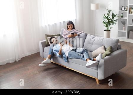 High angle view relaxed eastern lovers using gadgets at home Stock Photo