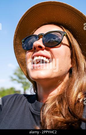 Close-up portrait of happy young woman with sunglasses and straw hat. Stock Photo