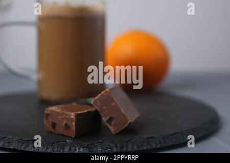 chocolate candy with coffee and orange slices on a grey tray with coffee and orange in the background. Handmade candies. Dessert and coffee Stock Photo