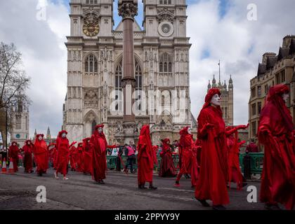 Performance activists Red Rebel Brigade march past Westminster Abbey as part of 'The Big One' Extinction Rebellion weekend protest April, 2023. Stock Photo