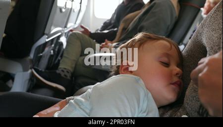 Cute baby asleep during flight. Infant toddler sleeping inside airplane Stock Photo