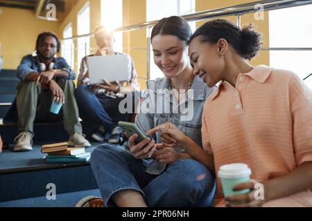 Group of students chatting and using gadgets while resting during break at college Stock Photo