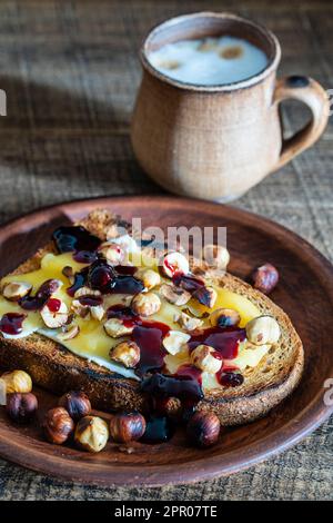 Bread toast with butter, roasted hazelnuts, honey, berry jam on plate ...