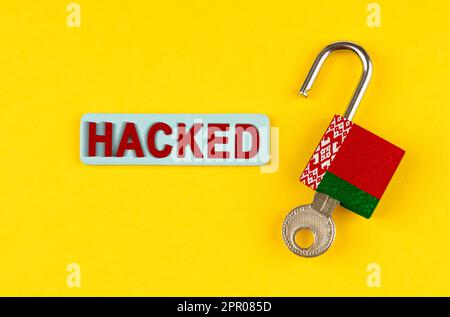 On the yellow surface is an open lock with the image of the flag of Belarus and a sticker with the inscription - hacked Stock Photo
