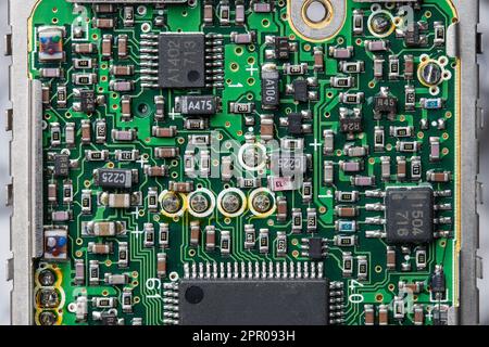 Old printed circuit board with radio components on background. Vintage circuit board with soldering trace, parts and microcircuits, close up, top view Stock Photo