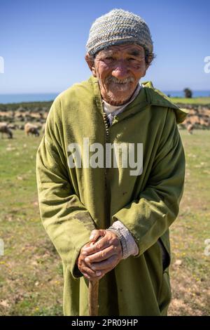 Portrait of an elderly shepherd dressed in a green djellaba herding his flock in the vicinity of Asilah. Stock Photo