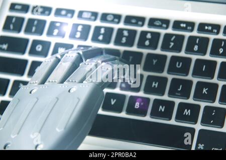 Robot hand while working on a computer keyboard . Stock Photo
