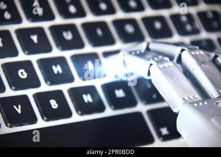 Robot hand working on a computer keyboard . Stock Photo