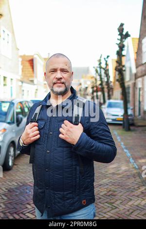 Attractive man is walking the street. Bearded hipster guy wearing casual clothes enjoys relaxing on a summer weekend. Stock Photo