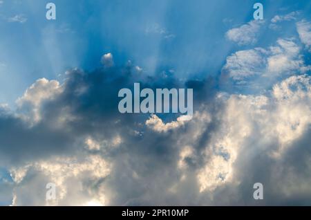 Sun rays through clouds in the blue morning sky Stock Photo