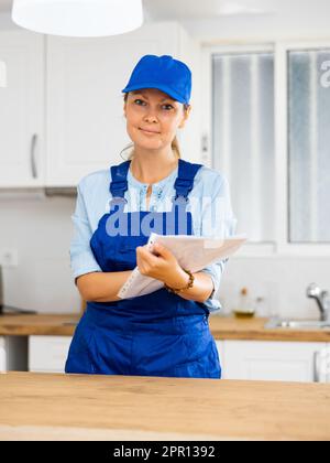 Woman house cleaner making notes in kitchen Stock Photo
