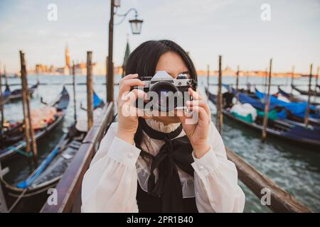 An Asian tourist in Venice takes a photo with her reflex camera Stock Photo