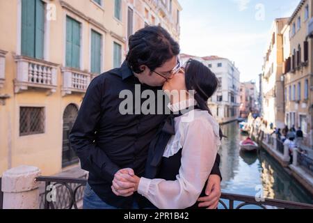 A mixed couple of lovers kissing in Venice, passionate moment Stock Photo