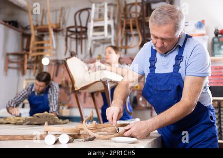 Professional elderly craftsman restorer in uniform renewing