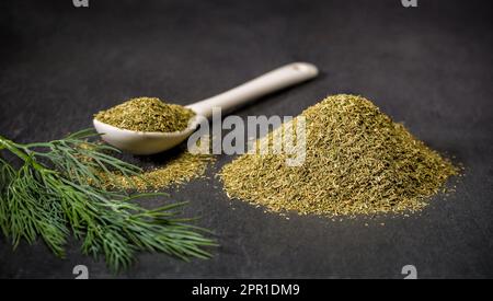 Aromatic spices dill. Spoon and pile of ground dried and fresh dill spice. Recipe ingredients. Stock Photo