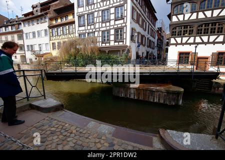 People wait to cross Pont du Faisan while in the open position. The bridge is a hydraulic, or swing bridge over the Ill River in Strasbourg, France. Stock Photo