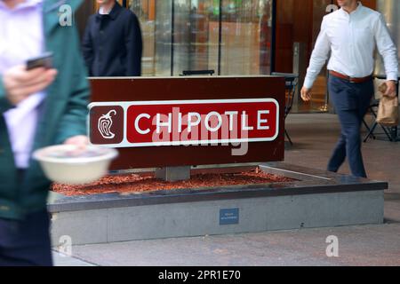 Office workers with takeout lunches walk past a Chipotle in Midtown Manhattan, New York. Chipotle is a fast casual Mexican style restaurant Stock Photo