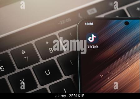New york, USA - April 25, 2023: TikTok app icon on smartphone screen close up view keyboard background Stock Photo