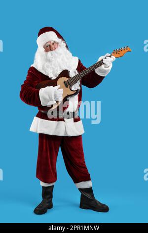Santa Claus playing electric guitar on blue background. Christmas music Stock Photo
