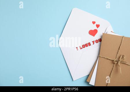 Love letter and stack of envelopes on light blue background, flat lay. Space for text Stock Photo