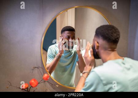 African American man looking at reflection in mirror and smiling Stock Photo