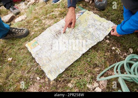 Los Gigantes, Cordoba, Argentina, April 6, 2023: An open map on a natural ground, one hand of an unknown person points to a place on it. Concept: orie Stock Photo