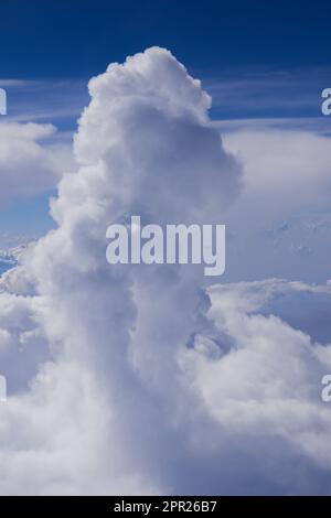 Cumulus and cumulonimbus rain clouds seen from aeroplane. Shot taken in flight against blue sky. Stock Photo