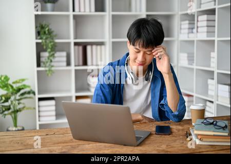 Asian college student sitting in the study room with laptop computer and books, preparing for the exam. Stock Photo