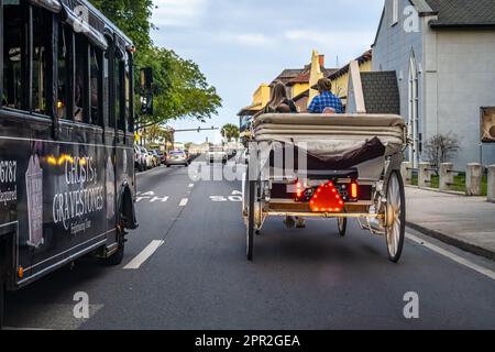 Horse-drawn carriage and a Ghosts & Gravestones tour bus on King Street approaching Matanzas Bay in Historic Old City St. Augustine, Florida. (USA) Stock Photo