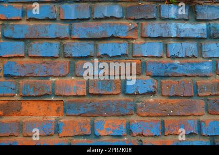 Closeup of weathered red brick wall with traces of blue paint background Stock Photo