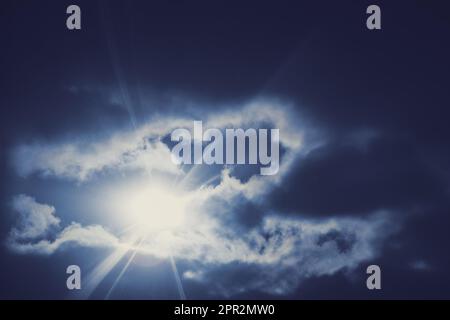 Rays of the sun through dark blue heavy clouds, sunlight. Sunbeams break through the dark lead clouds Stock Photo