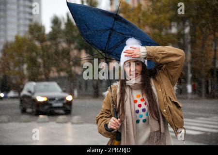 Woman with blue umbrella caught in gust of wind on street Stock Photo