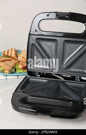 Modern grill maker and sandwiches on white table Stock Photo